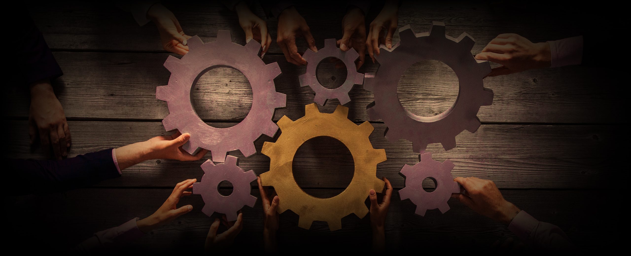 Business people joining gears Group of business people joining together silver and golden colored gears on table at workplace top view